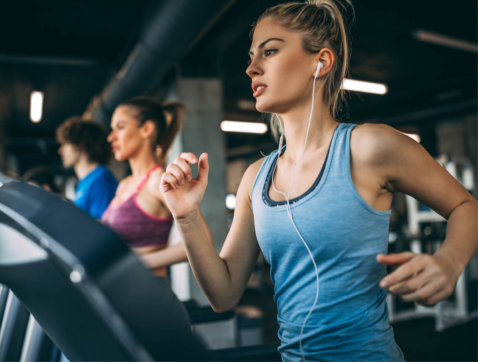 Young people running on a treadmill in health club.