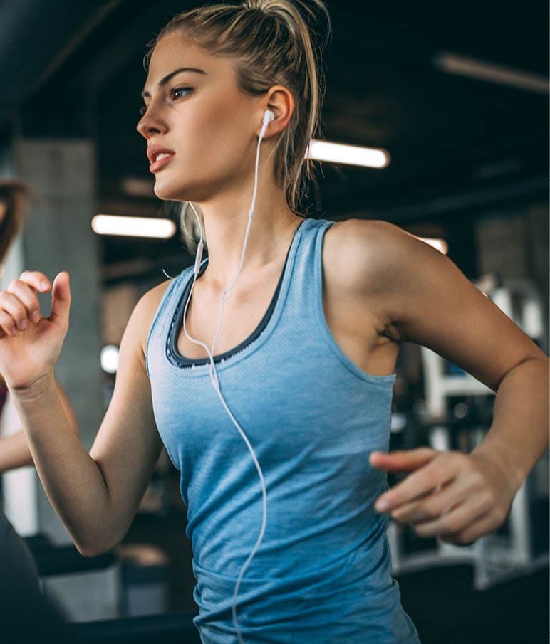 Young people running on a treadmill in health club.